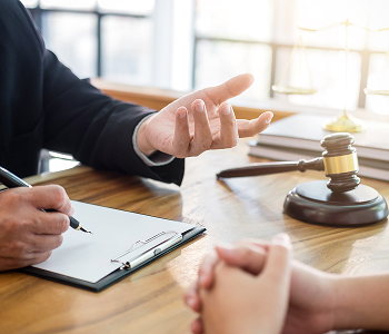 A lawyer and a client sit at a table, discussing legal documents