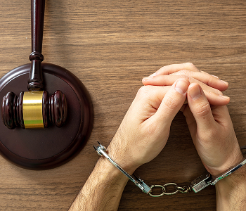 A gavel and handcuffs resting on a wooden table